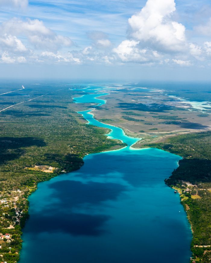 A breathtaking aerial shot of Bacalar Lagoon's turquoise waters and lush landscape. Ideal for travel and nature enthusiasts.