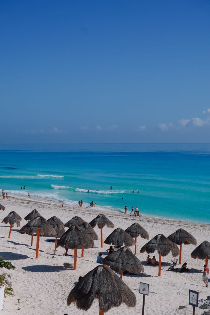 services-10 Beautiful Cancun beachscape with turquoise waters and thatched umbrellas.