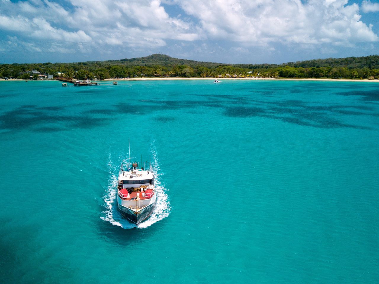 our-story-01 A boat navigates the turquoise Caribbean Sea near Corn Islands, offering a serene view of the Nicaraguan coastline.